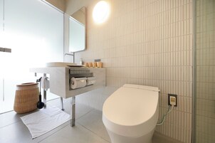 Ein modernes Badezimmer mit Toilette, Waschbecken und Spiegel.