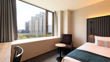 A hotel room with a large window, a bed, a chair, and a small table.