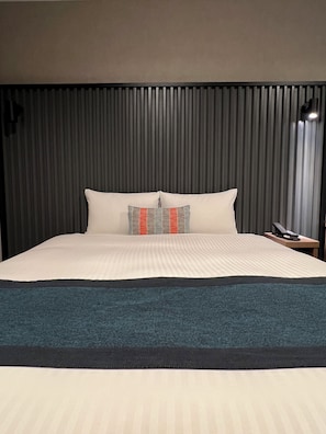 A hotel room with a large bed, a headboard with vertical slats, a bedside table with a phone, and a nightstand. - THE KNOT TOKYO Shinjuku (Tokyo)