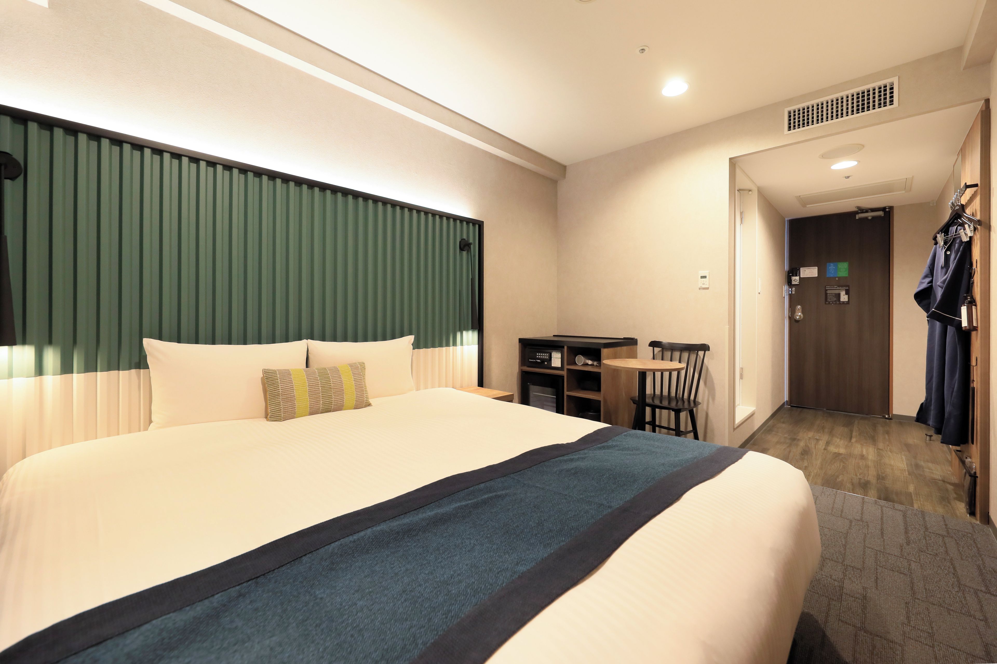 A hotel room with a large bed, a desk, and a chair.