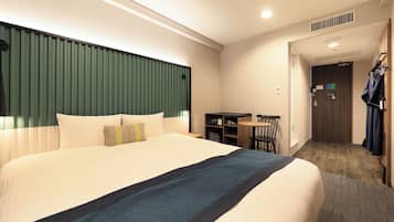 A hotel room with a large bed, a desk, and a chair.