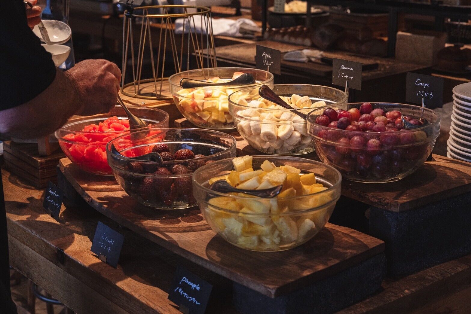 Een buffet met verschillende soorten fruit en een persoon die serveert.