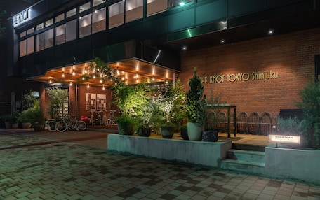 A hotel entrance with a brick facade, outdoor seating area, and potted plants.