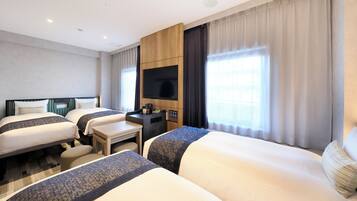 A hotel room with two beds, a desk, a flat-screen TV, and a large window with curtains.
