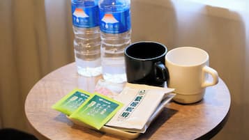Une table en bois avec deux bouteilles d’eau, une tasse noire, une tasse blanche et deux sachets de thé.