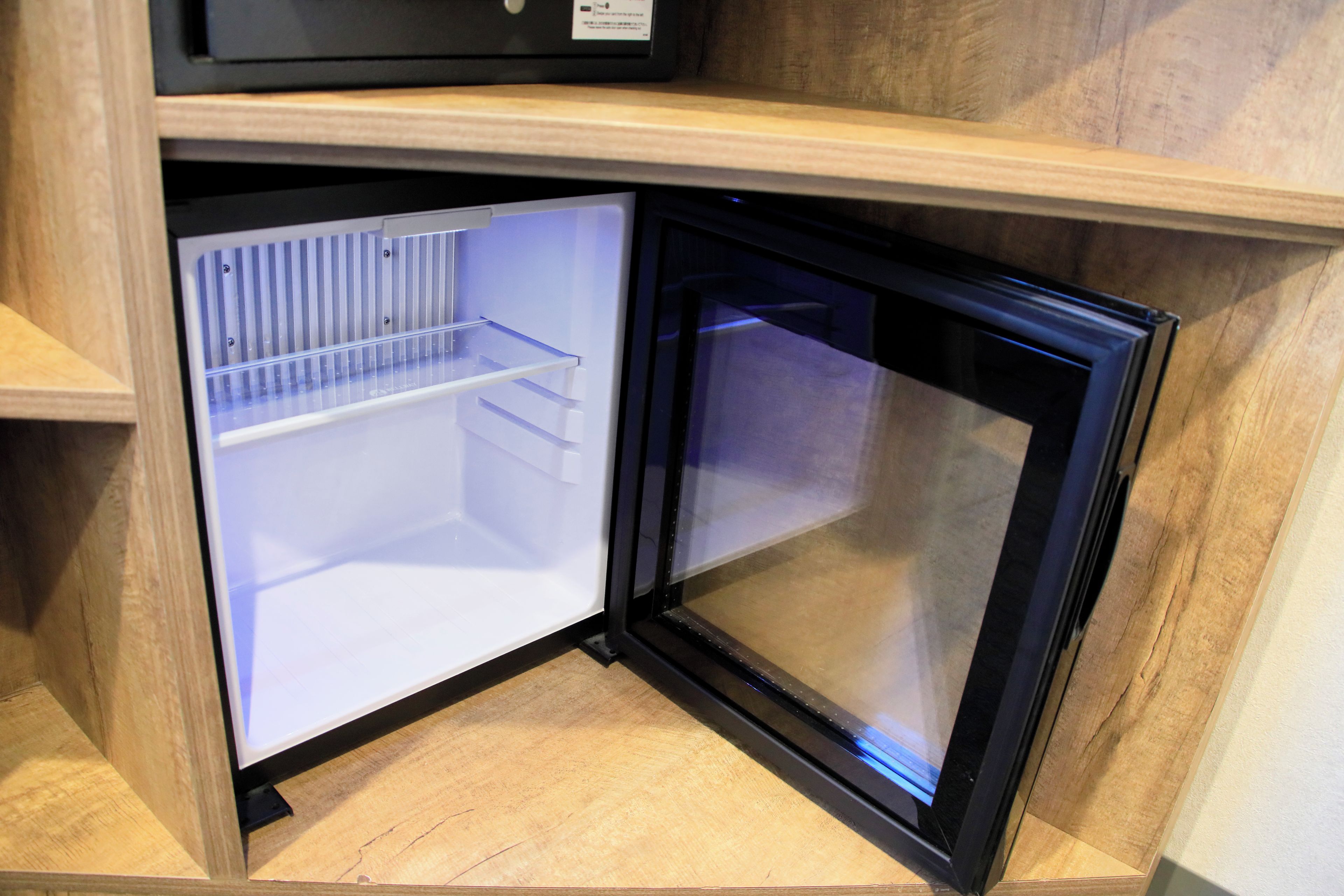 A compact refrigerator with a transparent door, a built-in shelf, and a freezer compartment.
