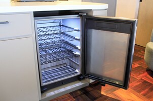 A compact refrigerator with multiple shelves and a freezer compartment, built into a white cabinetry.
