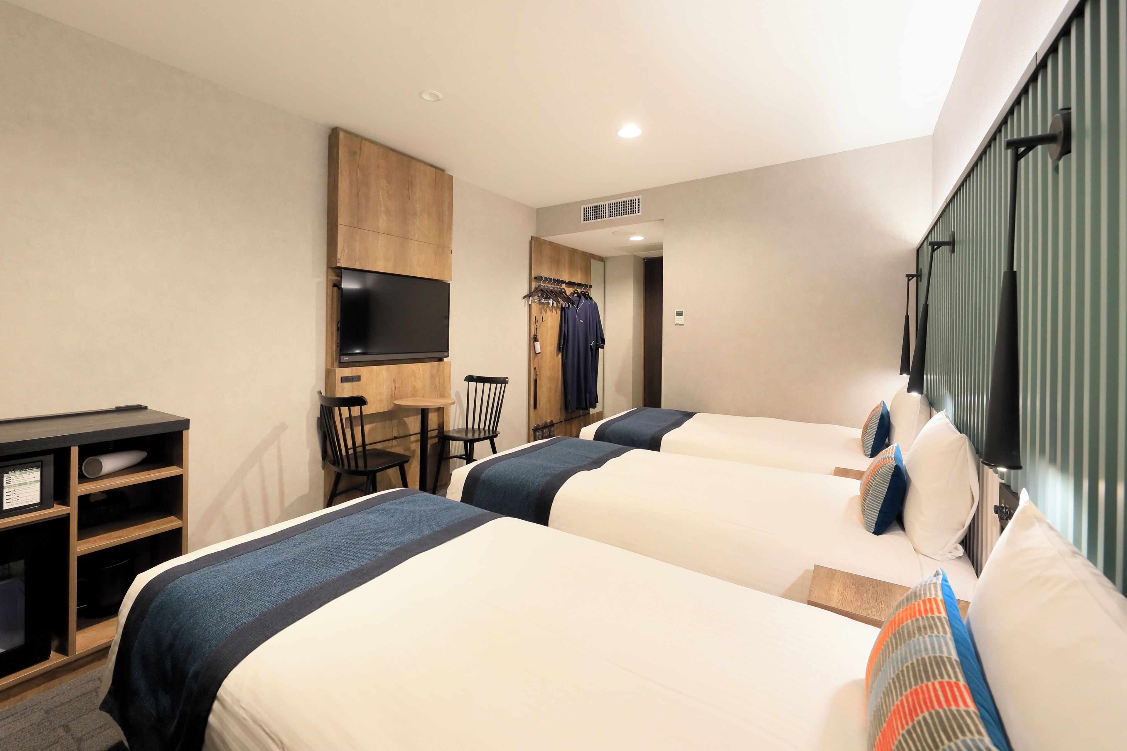 Quarto de hotel com duas camas, uma televisão, uma escrivaninha e uma cadeira.