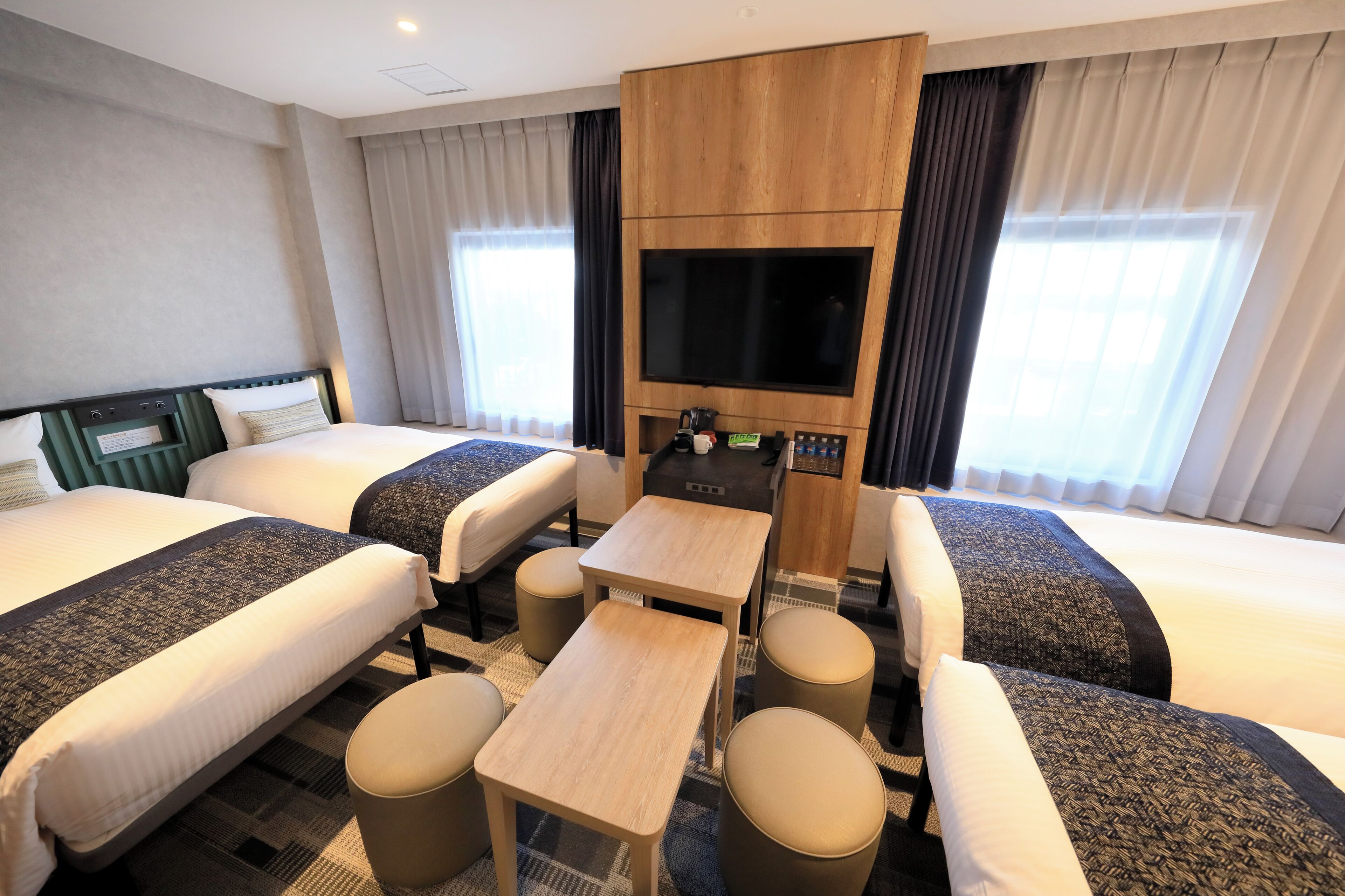 A hotel room with two beds, a TV, a small table, and a coffee maker.