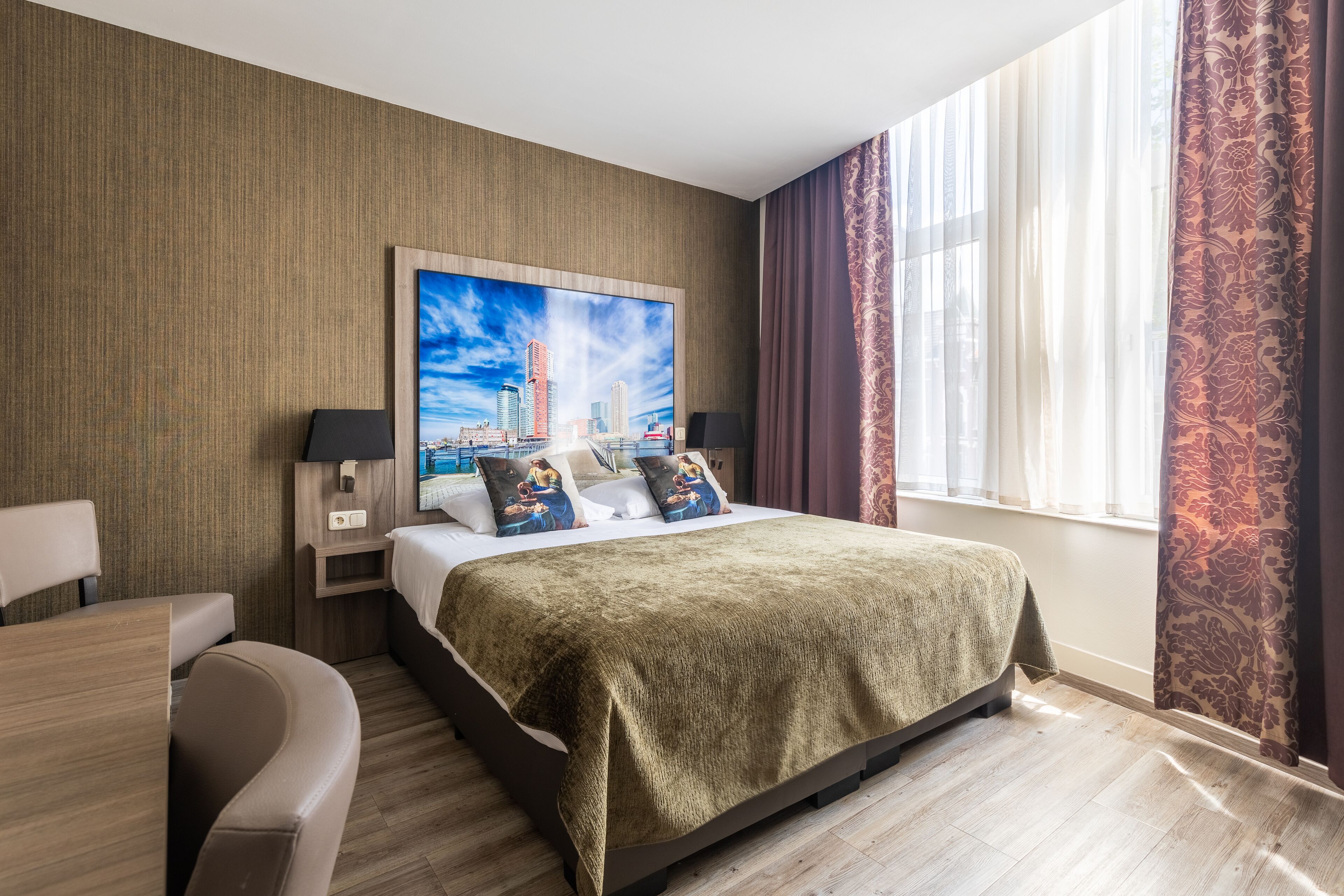 Quarto de hotel com uma cama grande, uma escrivaninha e uma cadeira.