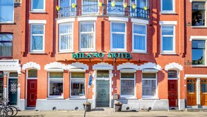 A red brick building with a curved balcony and a sign reading "MILANO HOTEL".