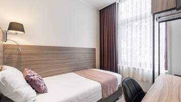 Una habitación de hotel con una cama, un escritorio y una lámpara.