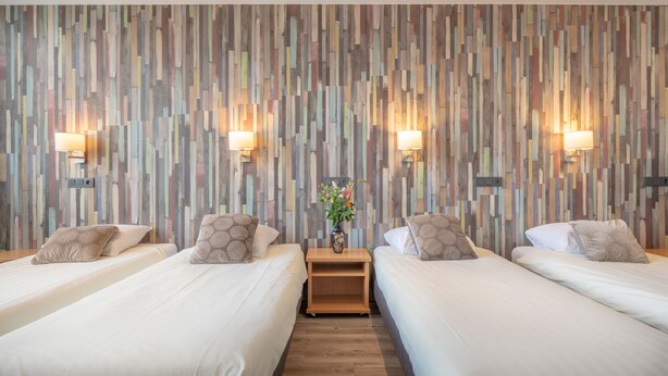 A hotel room with two beds, a wooden nightstand, and a wall with vertical wooden panels.