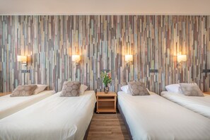 Una camera d'albergo con due letti, un comodino in legno e una parete rivestita in pannelli verticali di legno.