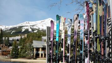 Skis leaning against a rack with a snow-capped mountain in the background.