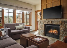 Una sala de estar con chimenea, un sofá, una mesa de centro y un televisor montado en la pared.
