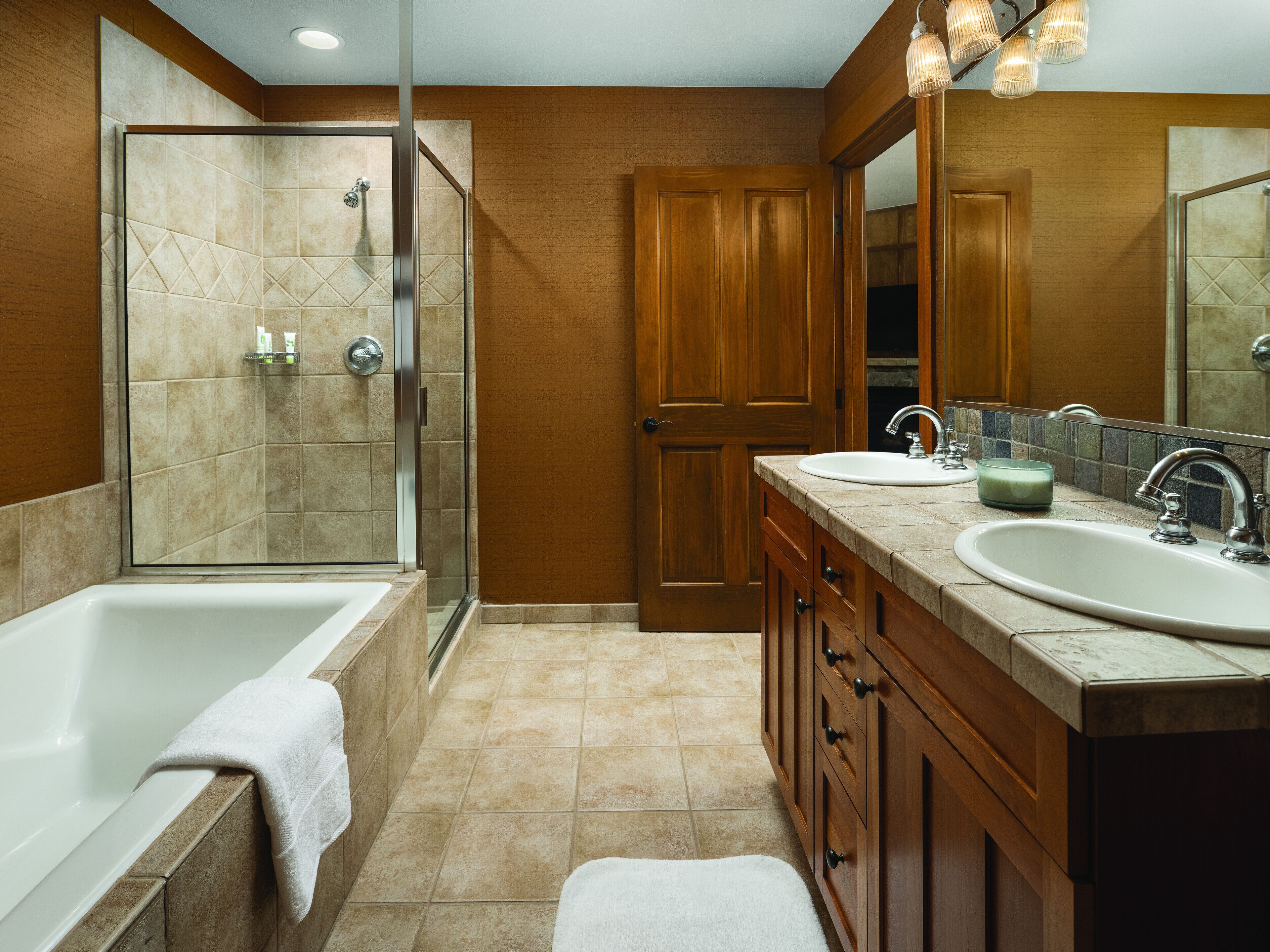 A bathroom with a shower, two sinks, and a large mirror.