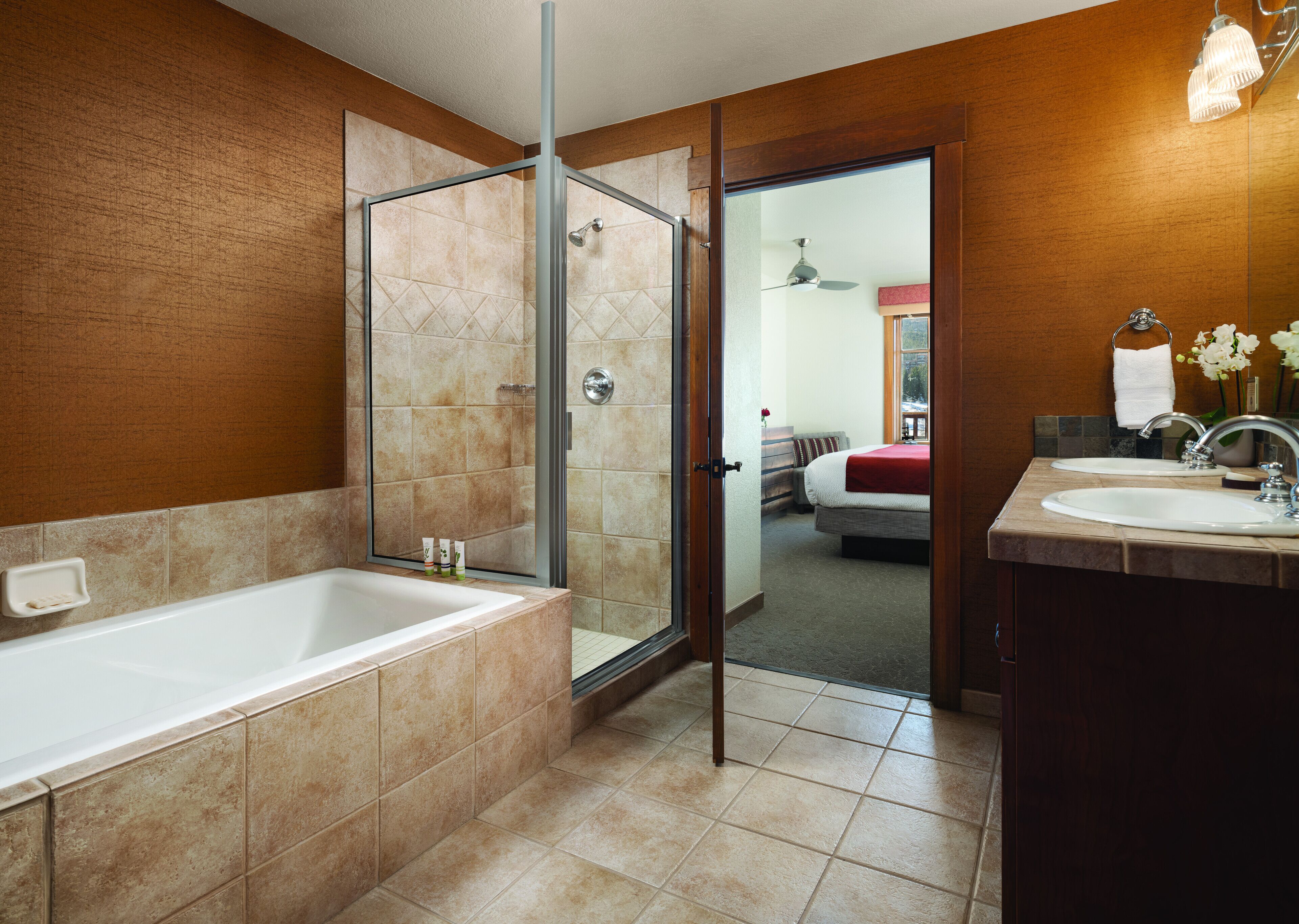A modern bathroom with a glass-enclosed shower, a large bathtub, and two sinks.