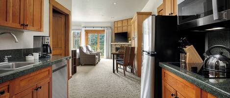 A kitchen with wooden cabinets, a stainless steel refrigerator, a coffee maker, and a dining area with chairs and a table.