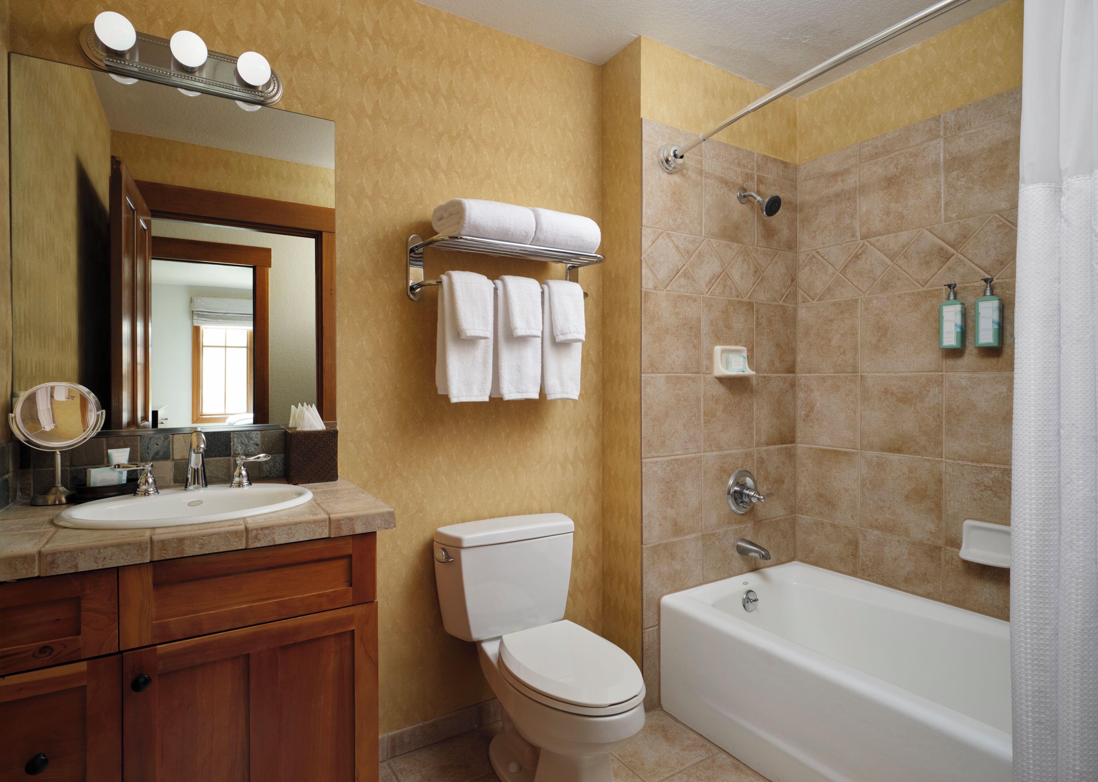 A bathroom with a sink, mirror, towel rack, toilet, and bathtub.