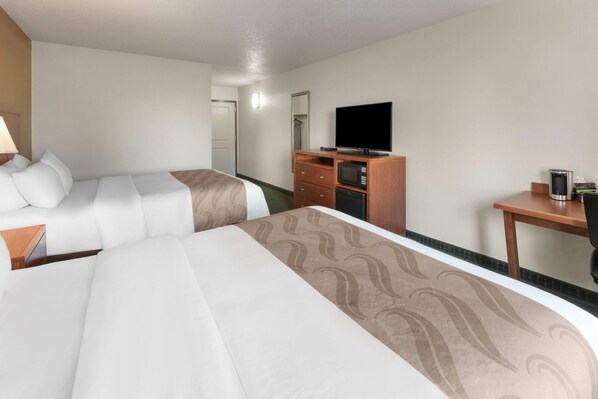 A hotel room with two beds, a TV, a desk, and a dresser.