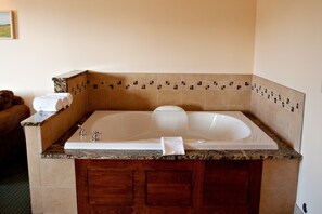 Bathroom features a bathtub, granite countertop, and wooden vanity with a mirror.