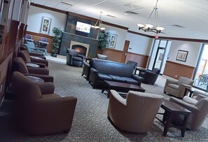 Relax in the inviting lobby with a fireplace, comfortable seating, and artwork on the walls.