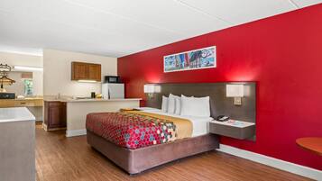 Habitación de hotel con cama, escritorio, microondas y pared roja.