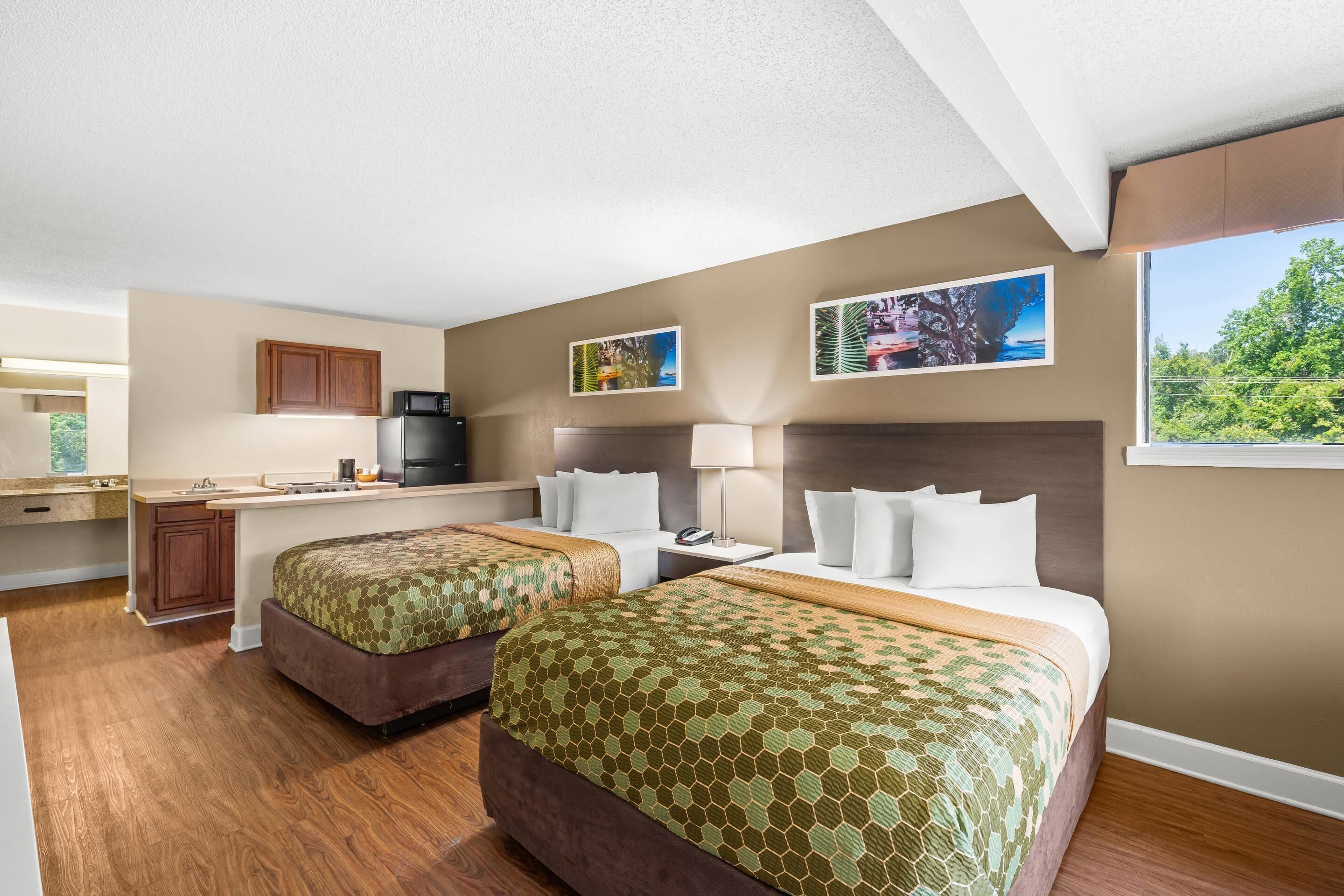 Habitación de hotel con dos camas, kitchenette y vistas al exterior.