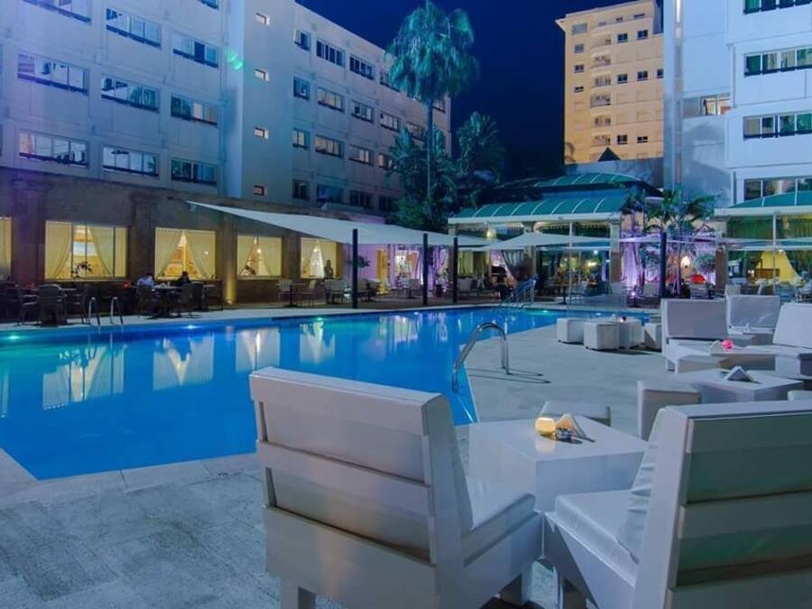 Una piscina al aire libre, sombrillas, sillones reclinables de piscina