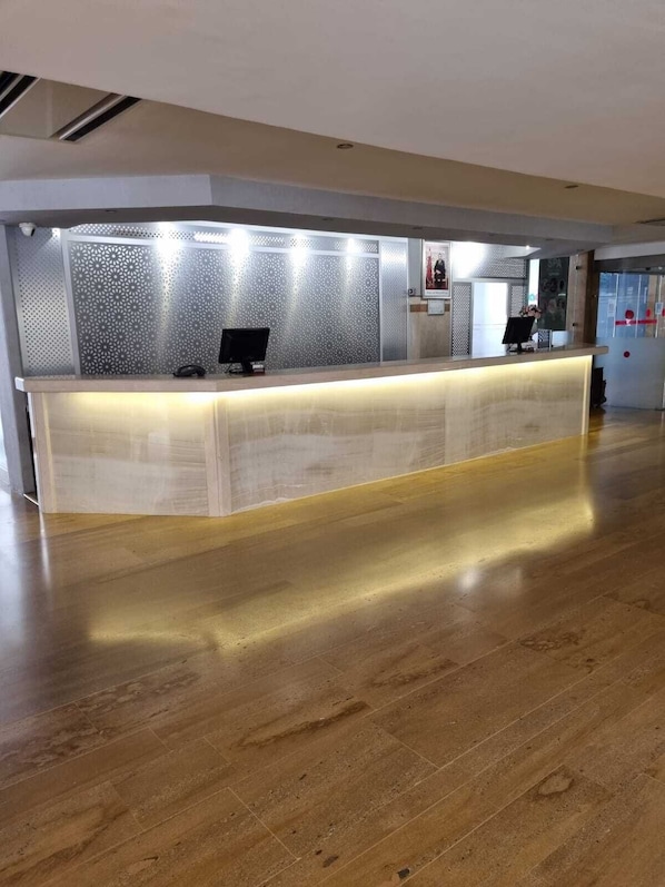 Un comptoir d’accueil au design moderne, agrémenté d’un mur à motifs et d’un plancher en bois.