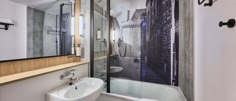 Un baño moderno con un espejo grande, un lavabo blanco y una ducha con mampara de vidrio.