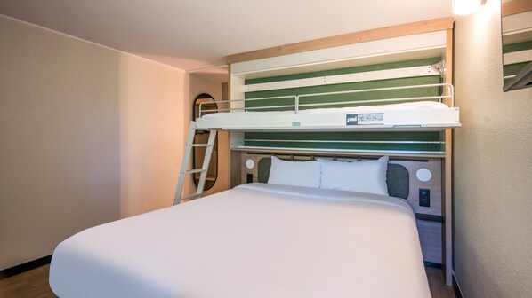 A bunk bed with a ladder, a single bed below, and a headboard with a green panel.