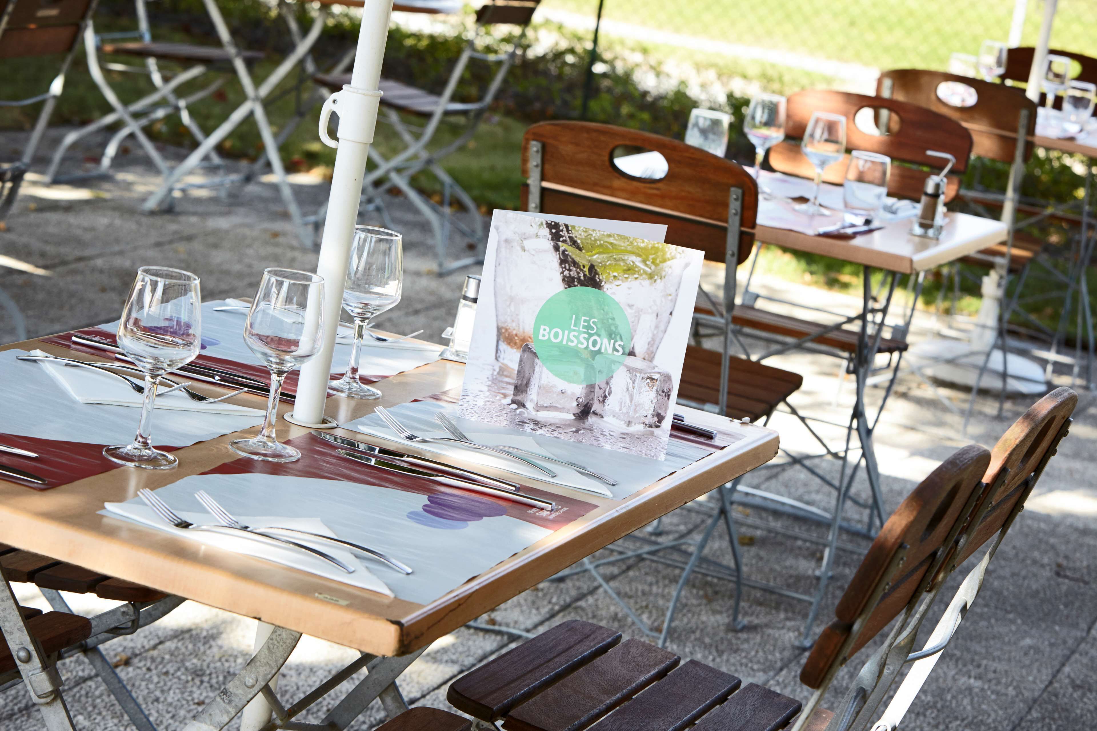 Een eettafel buiten gedekt, compleet met menu, glazen en bestek.