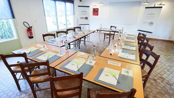 A conference room with hexagonal patterned floor tiles, wooden tables with name placards, and chairs.