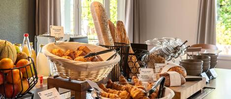 A breakfast buffet with various breads, pastries, and fruits.