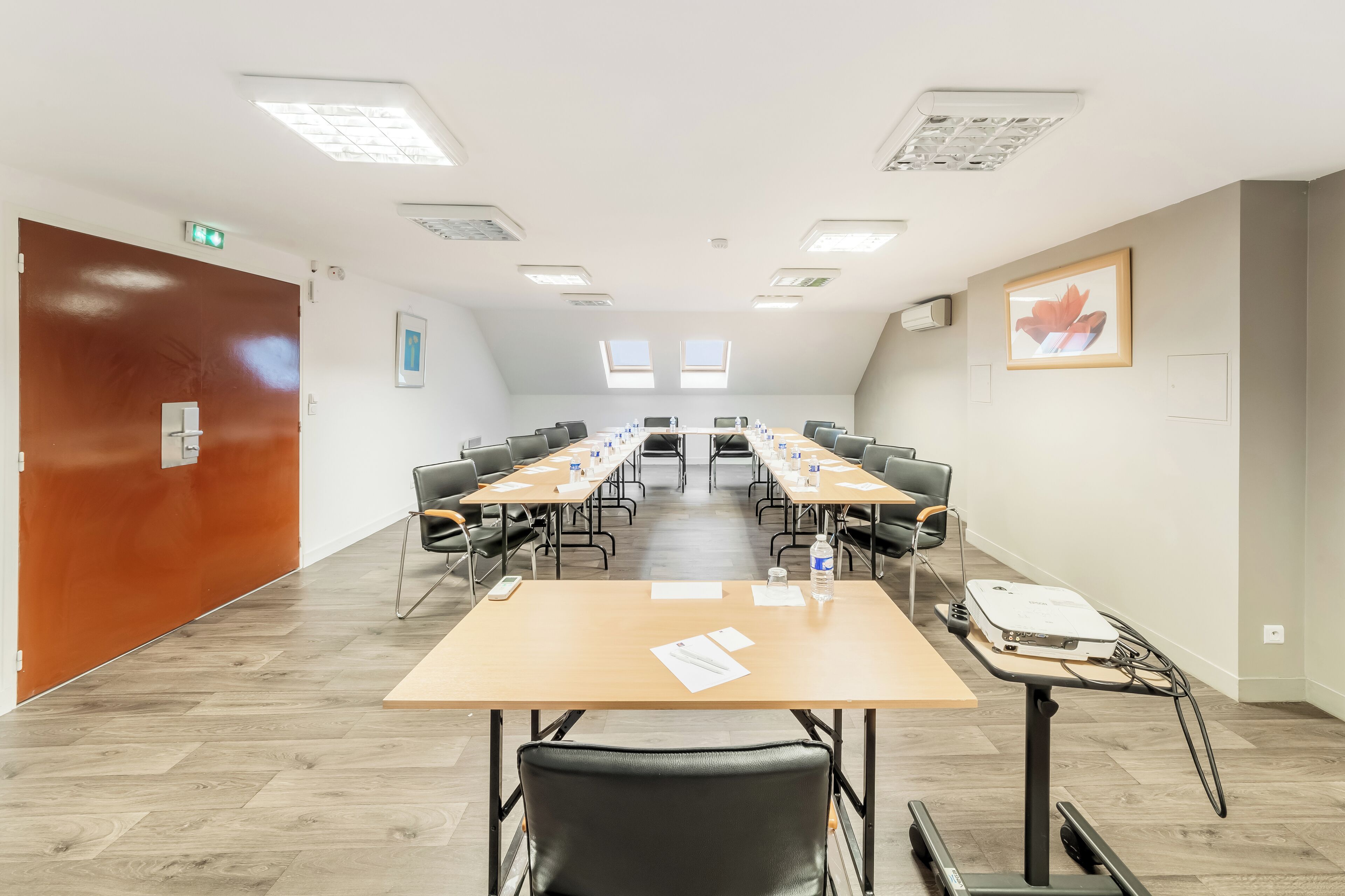 Une salle de conférence équipée de longues tables, de chaises et d’un projecteur.