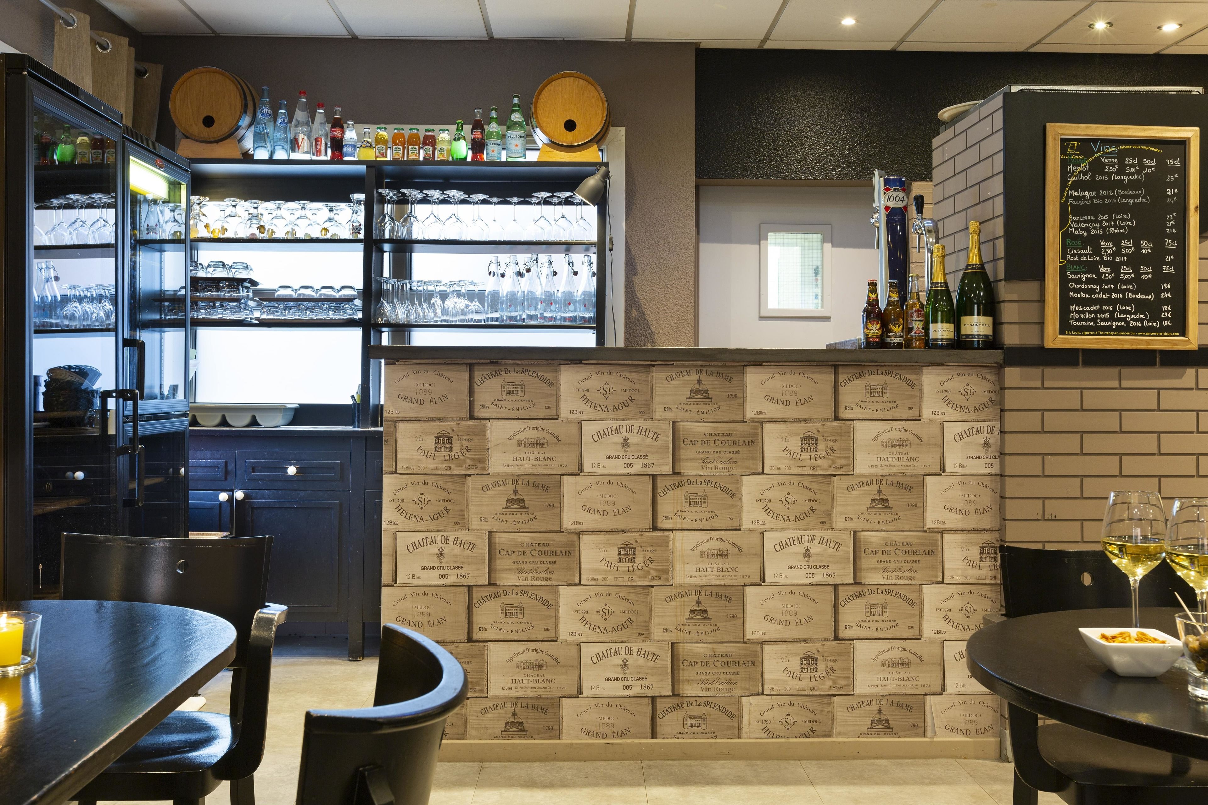 A restaurant interior with a bar area, wine bottles, and a menu board.