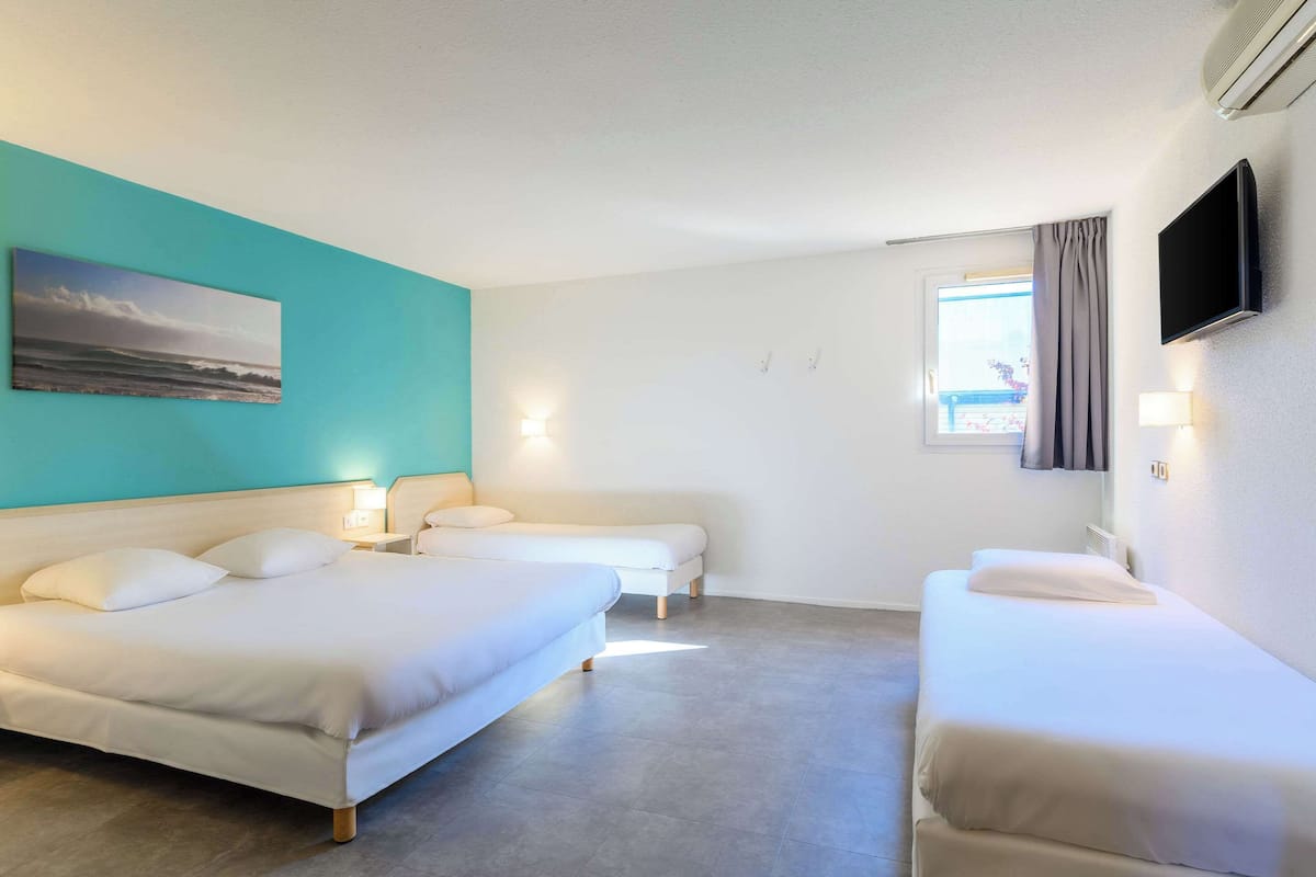 Ein Hotelzimmer mit zwei Betten, einem Fernseher und einem Bild an der Wand.