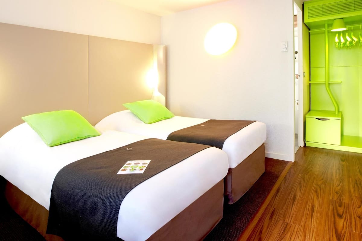 Ein Hotelzimmer mit zwei Betten, einer grĂĽnen Wand und einer grĂĽnen TĂĽr.