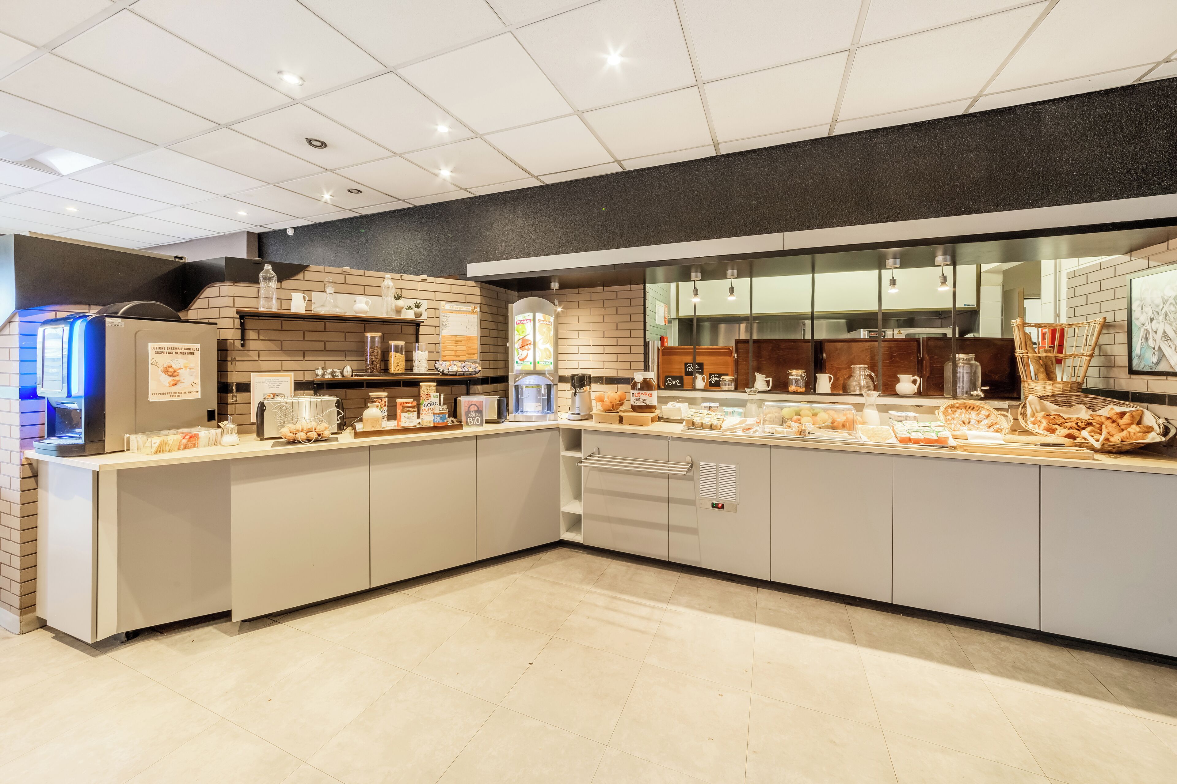 A modern kitchen with a long counter, various food items, and a brick wall.
