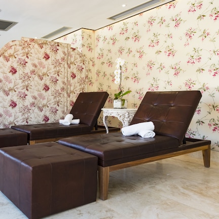 A spa room with multiple massage tables, each with a towel and a small plant.