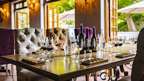 Une table dressée avec des verres et des bouteilles de vin, un canapé moelleux et une vue sur la verdure à l’extérieur.