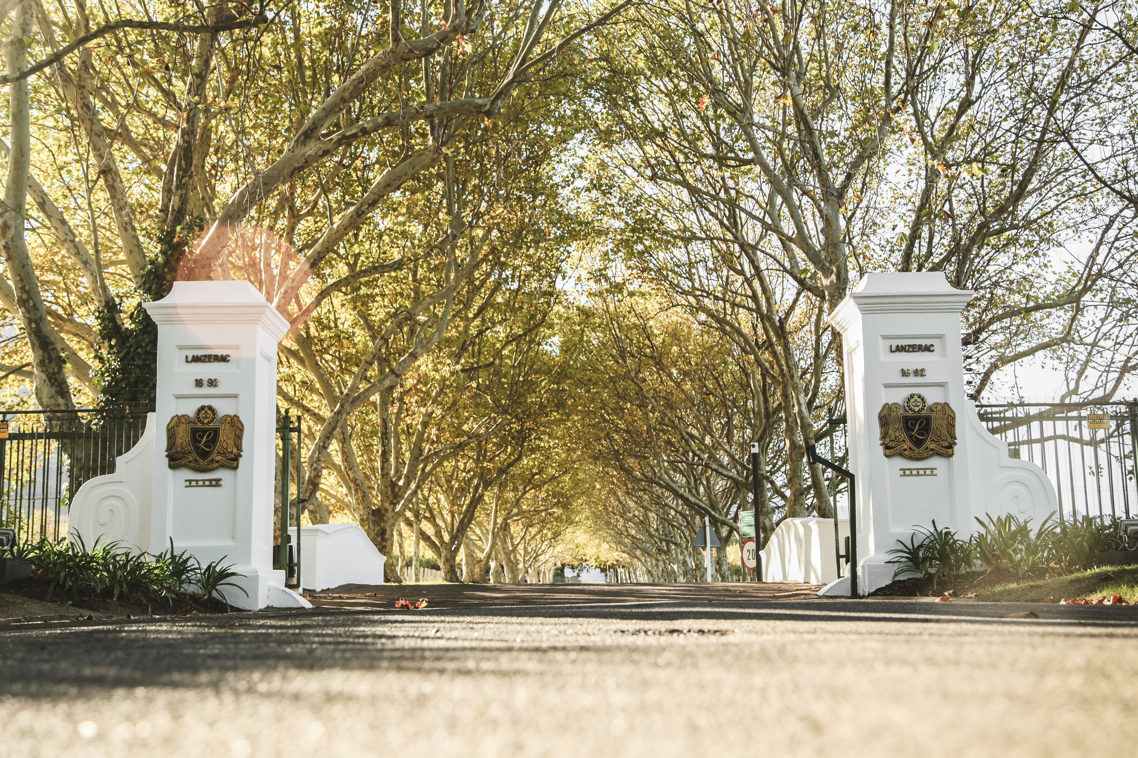 A gated entrance with two white pillars, each with a crest and the name 'LANZERAC'.