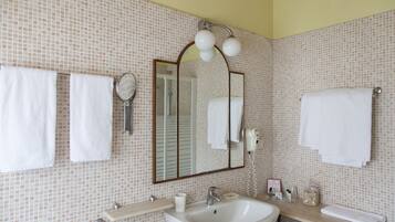 Un baño con lavamanos, espejo y dos toallas colgadas en la pared.
