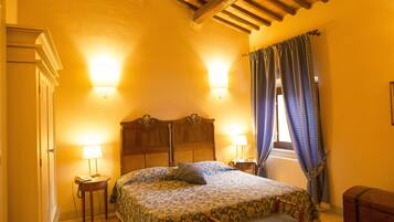 Una camera da letto con un letto, due lampade da comodino, una testiera in legno, una finestra con tende e una panca in legno.