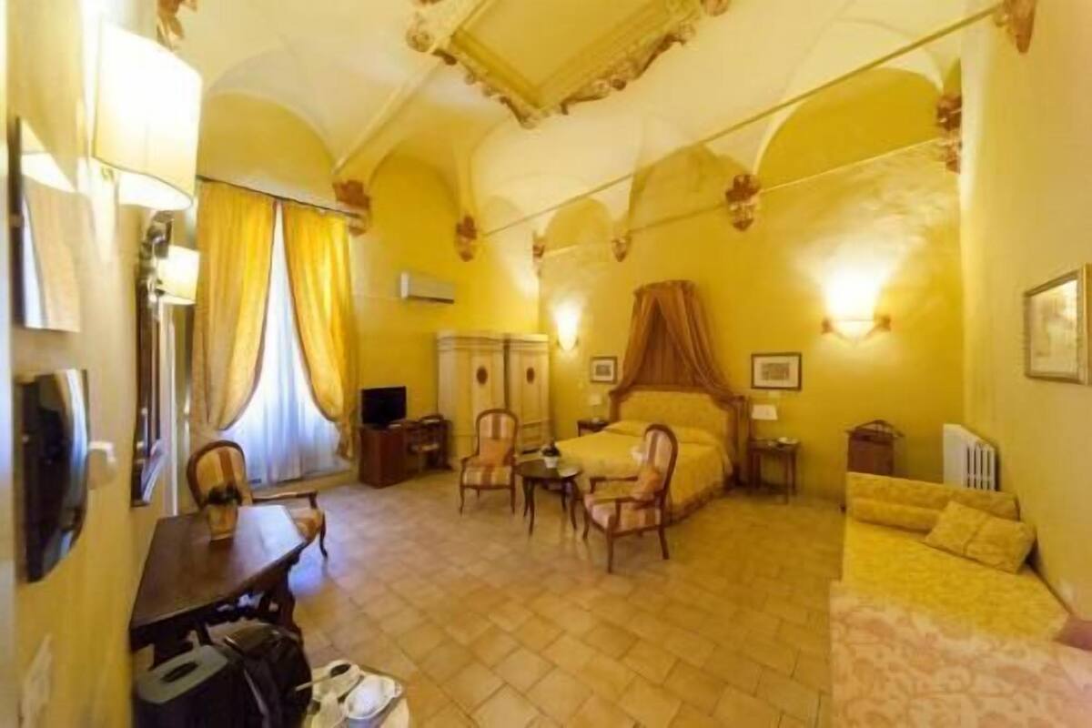 A hotel room with a bed, a desk, a chair, a television, and a window with curtains.