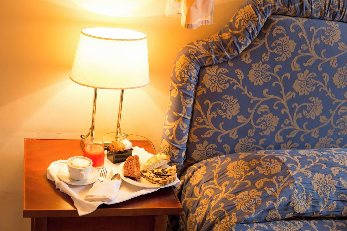 A neatly made breakfast table with a cup of coffee, a glass of orange juice, and pastries.