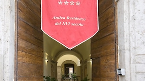 A red banner hanging over a wooden door with the text "HOTEL PALAZZO GUIDEROCCHI Antica Residenza del XVI secolo". - Palazzo Guiderocchi (Ascoli Piceno)