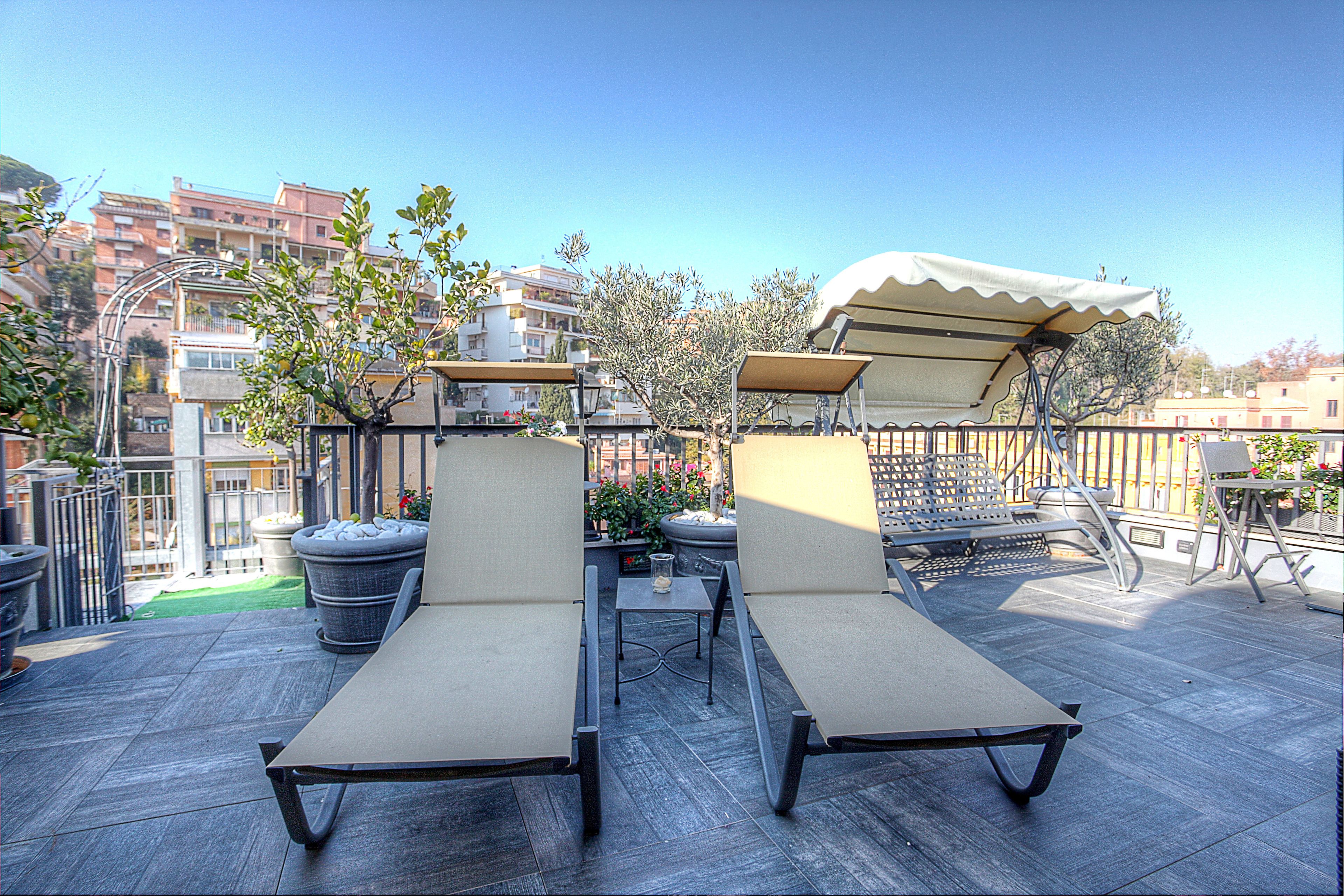 Eine Dachterrasse mit zwei Liegestühlen, einem Tisch und einem Blumentopf.